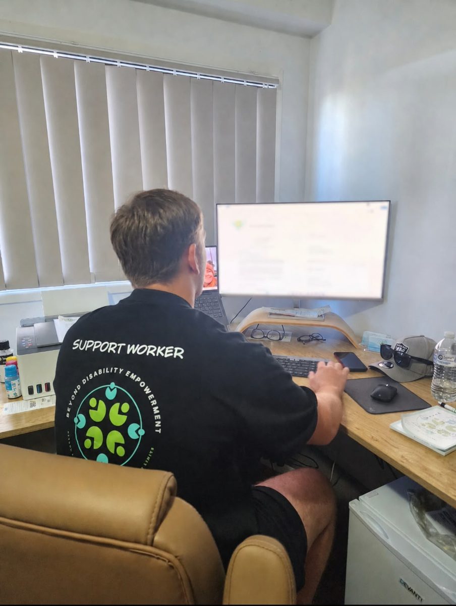 A BDE support worker at the office wearing a Beyond Disability Empowerment shirt