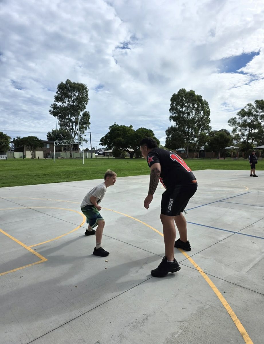 A support worker and participant playing basketball on an outdoor court