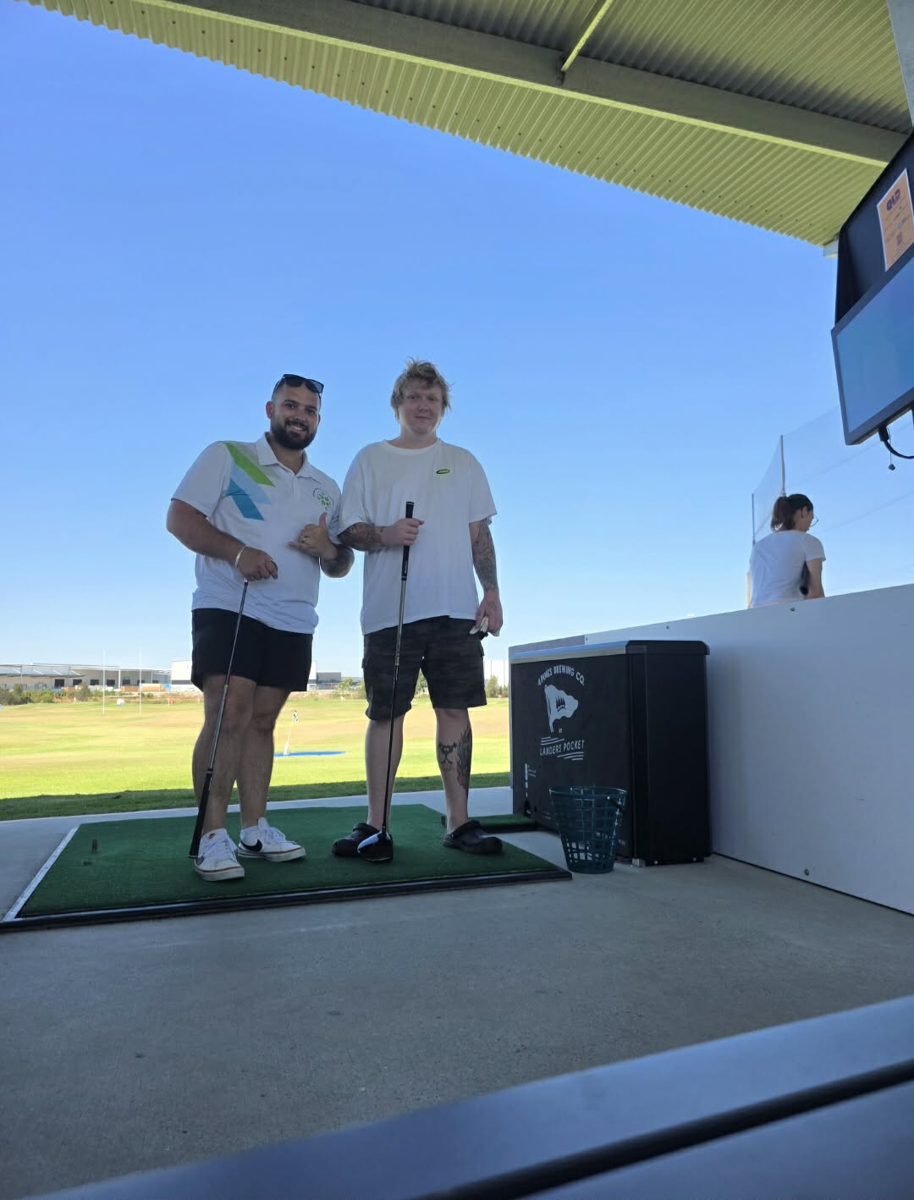 A support worker and participant at a golf driving range