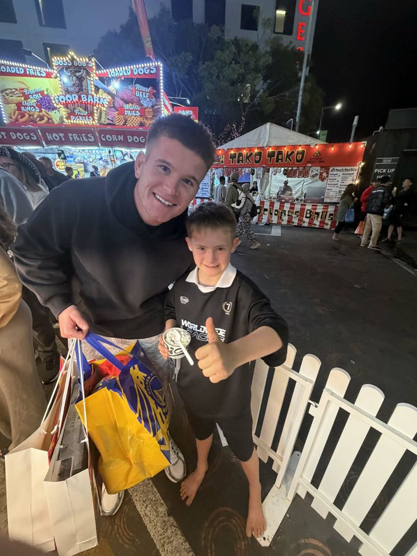 A support worker and participant with showbags at the Ekka